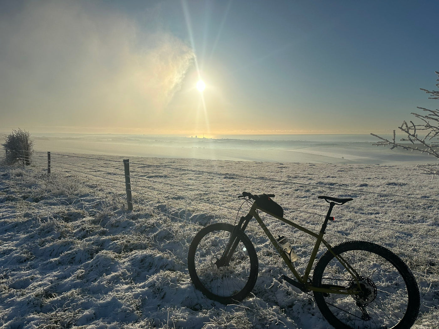 Cycling in winter, bicycle in a snowy field with hazy sunshine